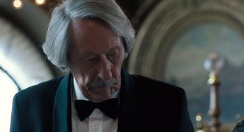 Movie still from “Mr. Bean's Holiday” (2007), directed by Steve Bendelack – An older man in a suit and a bow tie; Close Up shot, Over the shoulder angle