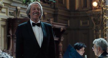 Movie still from “Mr. Bean's Holiday” (2007), directed by Steve Bendelack – An older man in a tuxedo smiling for the camera; Medium shot, Low angle