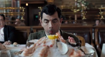 Movie still from “Mr. Bean's Holiday” (2007), directed by Steve Bendelack – A man in a brown jacket is eating food; Close Up shot, Low angle
