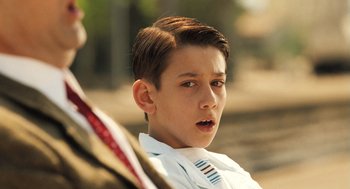 Movie still from “Mr. Bean's Holiday” (2007), directed by Steve Bendelack – A young boy in a white shirt and a tie; Close Up shot, Over the shoulder angle