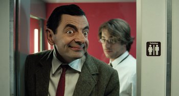 Movie still from “Mr. Bean's Holiday” (2007), directed by Steve Bendelack – A man in a suit and tie next to another man in a suit and tie; Close Up shot, Low angle