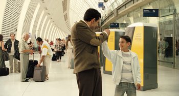 Movie still from “Mr. Bean's Holiday” (2007), directed by Steve Bendelack – A man and a boy high fiving each other in an airport; Medium shot, Low angle