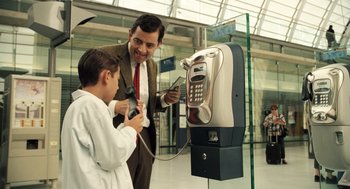 Movie still from “Mr. Bean's Holiday” (2007), directed by Steve Bendelack – A man and a boy standing in front of a payphone; Medium shot, Low angle