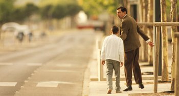 Movie still from “Mr. Bean's Holiday” (2007), directed by Steve Bendelack – A man and a boy walking down a sidewalk; Wide shot, Over the shoulder angle