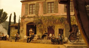 Movie still from “Mr. Bean's Holiday” (2007), directed by Steve Bendelack – A group of people sitting at tables outside of a restaurant; Extreme Wide shot, Low angle
