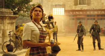 Movie still from “Mr. Bean's Holiday” (2007), directed by Steve Bendelack – A woman holding a tray with a drink in her hand; Medium shot, Low angle