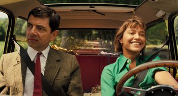 Movie still from “Mr. Bean's Holiday” (2007), directed by Steve Bendelack – A man and a woman sitting in the back of a car; Medium shot, Low angle