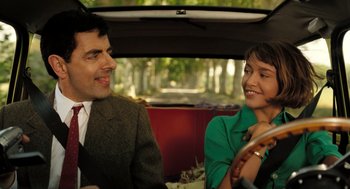 Movie still from “Mr. Bean's Holiday” (2007), directed by Steve Bendelack – A man and a woman sitting in the back of a car; Medium shot, Low angle
