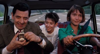 Movie still from “Mr. Bean's Holiday” (2007), directed by Steve Bendelack – A man and a woman and a child in a car; Medium shot, High angle