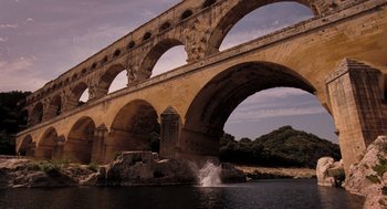 Movie still from “Mr. Bean's Holiday” (2007), directed by Steve Bendelack – A large stone bridge over a body of water; Extreme Wide shot, Low angle