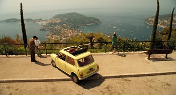 Movie still from “Mr. Bean's Holiday” (2007), directed by Steve Bendelack – A yellow car parked on the side of a road; Extreme Wide shot, High angle