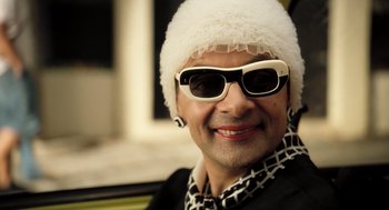 Movie still from “Mr. Bean's Holiday” (2007), directed by Steve Bendelack – A man wearing sunglasses and a white hat; Close Up shot, Low angle
