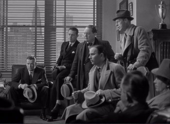 Movie still from “Mr. Deeds Goes to Town” (1936), directed by Frank Capra – A black and white photo of a group of men in suits and hats; Wide shot, High angle