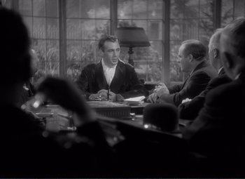 Movie still from “Mr. Deeds Goes to Town” (1936), directed by Frank Capra – A group of people sitting around a table; Medium shot, Over the shoulder angle