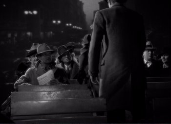Movie still from “Mr. Deeds Goes to Town” (1936), directed by Frank Capra – A black and white photo of a group of men standing around; Wide shot, High angle