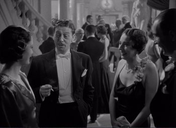 Movie still from “Mr. Deeds Goes to Town” (1936), directed by Frank Capra – A man and two women in formal wear talking to each other; Medium shot, Over the shoulder angle