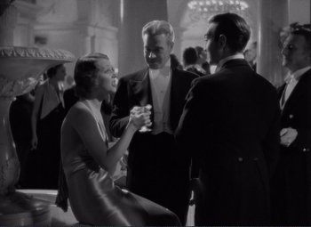 Movie still from “Mr. Deeds Goes to Town” (1936), directed by Frank Capra – A group of people standing in a room talking to each other; Medium shot, High angle