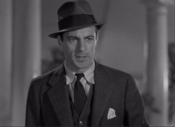 Movie still from “Mr. Deeds Goes to Town” (1936), directed by Frank Capra – A black and white photo of a man wearing a suit and a hat; Close Up shot, Low angle