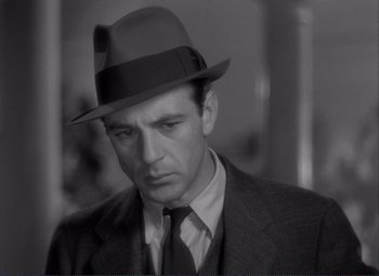 Movie still from “Mr. Deeds Goes to Town” (1936), directed by Frank Capra – A black and white photo of a man in a suit and a hat; Close Up shot, Low angle