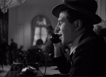 Movie still from “Mr. Deeds Goes to Town” (1936), directed by Frank Capra – A black and white photo of a man talking on a phone; Close Up shot, Low angle