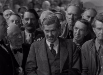 Movie still from “Mr. Deeds Goes to Town” (1936), directed by Frank Capra – A group of men standing next to each other in a crowd; Medium shot, High angle