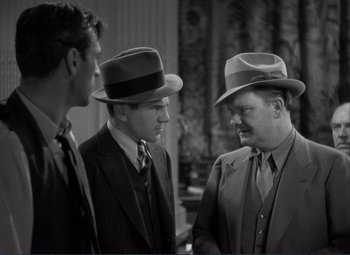 Movie still from “Mr. Deeds Goes to Town” (1936), directed by Frank Capra – A group of men in suits and hats talking; Medium shot, Over the shoulder angle