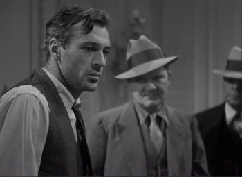 Movie still from “Mr. Deeds Goes to Town” (1936), directed by Frank Capra – A man wearing a hat and a tie standing next to another man wearing a hat; Medium shot, Over the shoulder angle