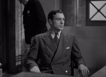 Movie still from “Mr. Deeds Goes to Town” (1936), directed by Frank Capra – A man in a suit and tie sitting at a table; Medium shot, Low angle