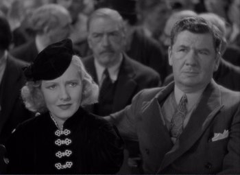 Movie still from “Mr. Deeds Goes to Town” (1936), directed by Frank Capra – An old photo of a man and a woman; Close Up shot, Low angle