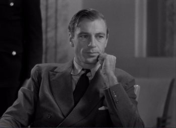 Movie still from “Mr. Deeds Goes to Town” (1936), directed by Frank Capra – An old photo of a man in a suit; Close Up shot, Over the shoulder angle