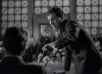 Movie still from “Mr. Deeds Goes to Town” (1936), directed by Frank Capra – A black and white photo of a man holding a pen; Medium shot, Over the shoulder angle