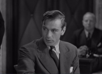 Movie still from “Mr. Deeds Goes to Town” (1936), directed by Frank Capra – A man wearing a suit and tie sitting in front of another man in a suit; Close Up shot, Over the shoulder angle