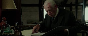 Movie still from “Mr. Holmes” (2015), directed by Bill Condon – An older man in a suit is writing on a piece of paper; Close Up shot, Low angle