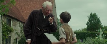 Movie still from “Mr. Holmes” (2015), directed by Bill Condon – An old man and a young boy talking to each other; Medium shot, Over the shoulder angle