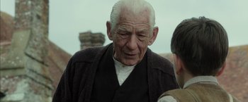 Movie still from “Mr. Holmes” (2015), directed by Bill Condon – An old man with white hair is looking at the camera; Close Up shot, Over the shoulder angle