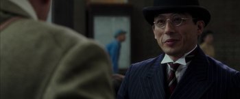 Movie still from “Mr. Holmes” (2015), directed by Bill Condon – A man in a suit and hat standing in front of a mirror; Close Up shot, Over the shoulder angle