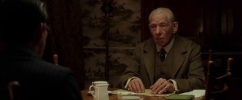 Movie still from “Mr. Holmes” (2015), directed by Bill Condon – An older man sitting at a table with a cup of coffee; Close Up shot, Over the shoulder angle