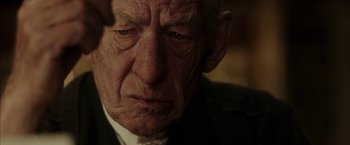 Movie still from “Mr. Holmes” (2015), directed by Bill Condon – An old man with wrinkled face looking at the camera; Close Up shot, Over the shoulder angle