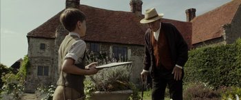 Movie still from “Mr. Holmes” (2015), directed by Bill Condon – An older man and a young boy in a garden; Medium shot, Over the shoulder angle