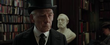 Movie still from “Mr. Holmes” (2015), directed by Bill Condon – An older man in a suit and hat next to a bust; Close Up shot, Over the shoulder angle