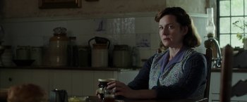 Movie still from “Mr. Holmes” (2015), directed by Bill Condon – A woman sitting at a kitchen table holding a jar; Medium shot, Over the shoulder angle