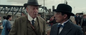 Movie still from “Mr. Holmes” (2015), directed by Bill Condon – Two older men in suits and hats talking to each other; Close Up shot, Over the shoulder angle
