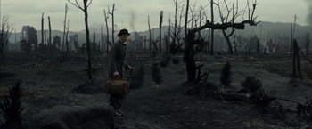 Movie still from “Mr. Holmes” (2015), directed by Bill Condon – A man holding a suitcase walking through a burned forest; Wide shot, High angle
