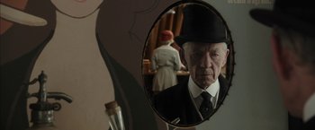 Movie still from “Mr. Holmes” (2015), directed by Bill Condon – An older man in a suit and hat looking into a mirror; Close Up shot, Over the shoulder angle
