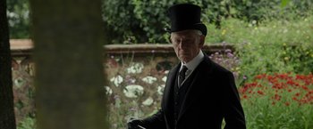 Movie still from “Mr. Holmes” (2015), directed by Bill Condon – An older man in a top hat and a suit; Medium shot, Over the shoulder angle