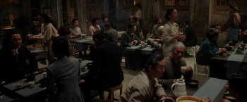 Movie still from “Mr. Holmes” (2015), directed by Bill Condon – A group of people sitting at tables in a room; Wide shot, High angle