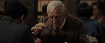 Movie still from “Mr. Holmes” (2015), directed by Bill Condon – An old man in a suit and tie eating a piece of food from a spoon; Close Up shot, Over the shoulder angle