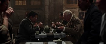 Movie still from “Mr. Holmes” (2015), directed by Bill Condon – A group of men sitting at a table with plates of food; Medium shot, High angle