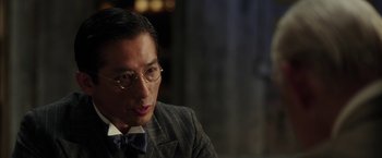 Movie still from “Mr. Holmes” (2015), directed by Bill Condon – A person wearing glasses and a suit; Close Up shot, Over the shoulder angle