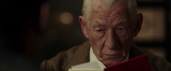 Movie still from “Mr. Holmes” (2015), directed by Bill Condon – An old man sitting in front of a red book; Close Up shot, Low angle